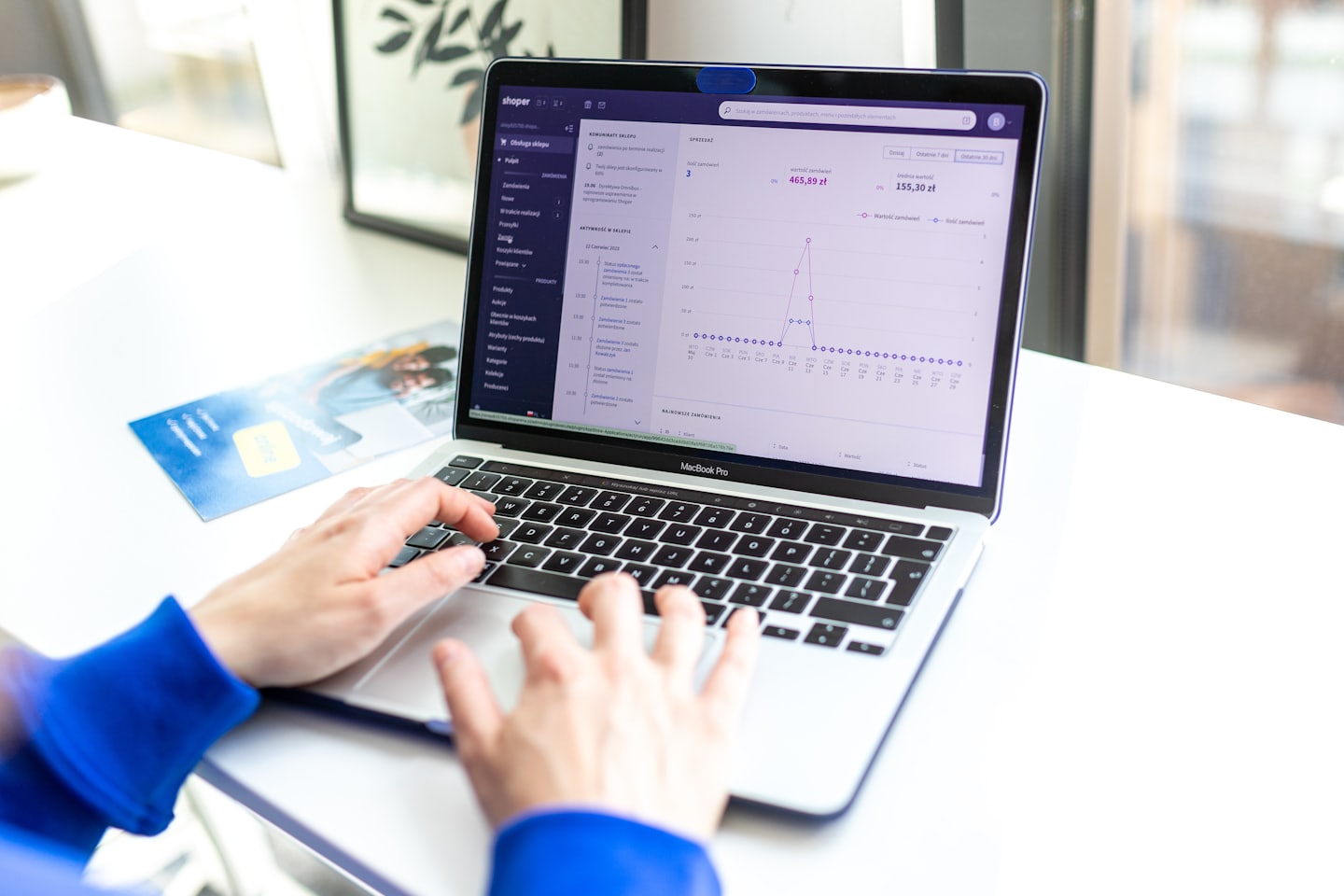 Hands typing on a laptop showing e-commerce sales data.