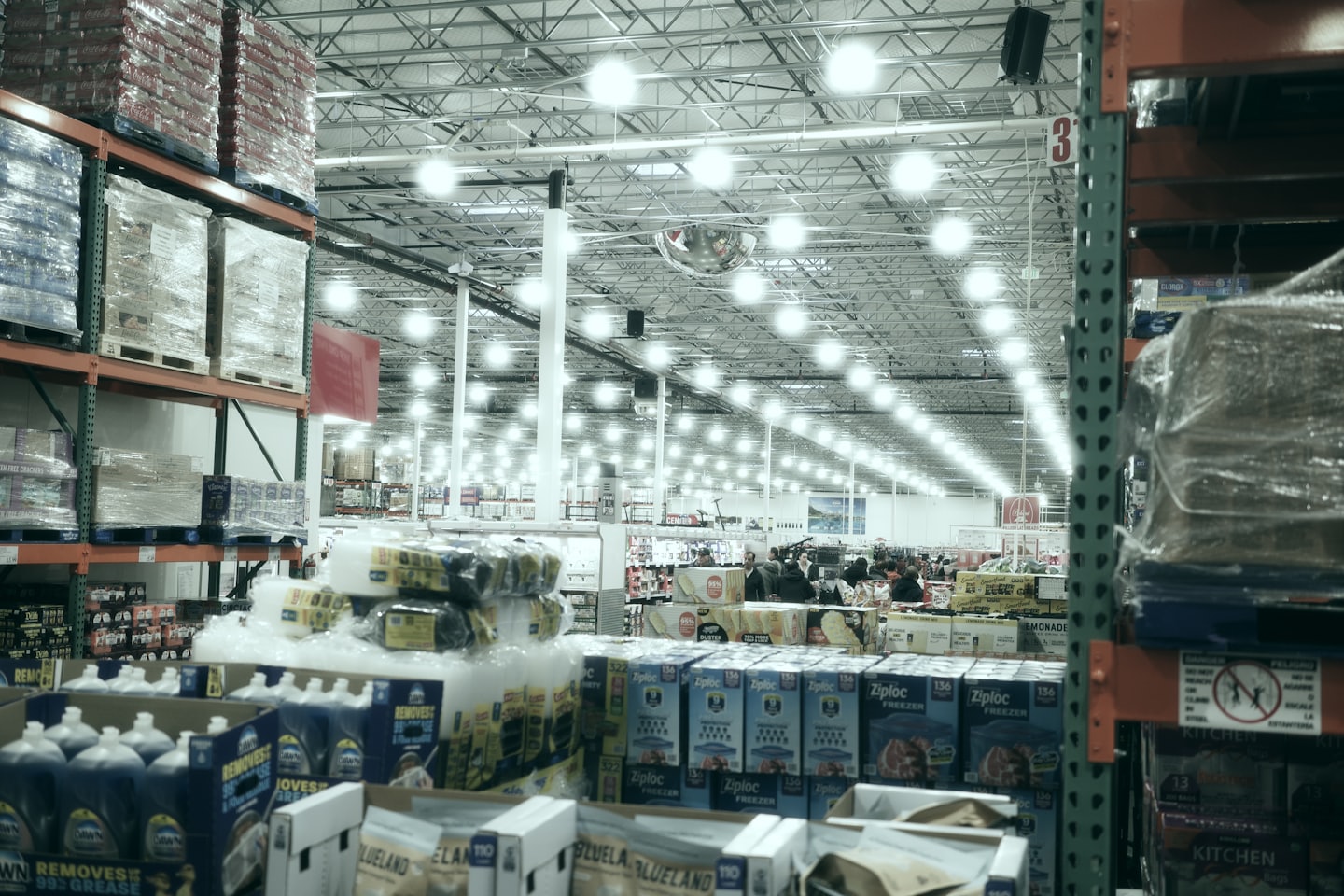 Customers browsing in a brightly lit warehouse store with tall shelves.